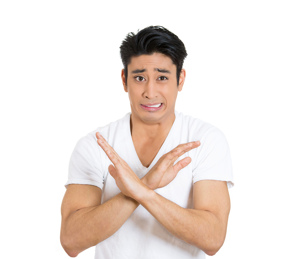 Closeup portrait, worried young man showing x sign to stop talking, cut it out, dont go there, isolated white background. Negative emotion facial expression feelings, signs symbols, body language